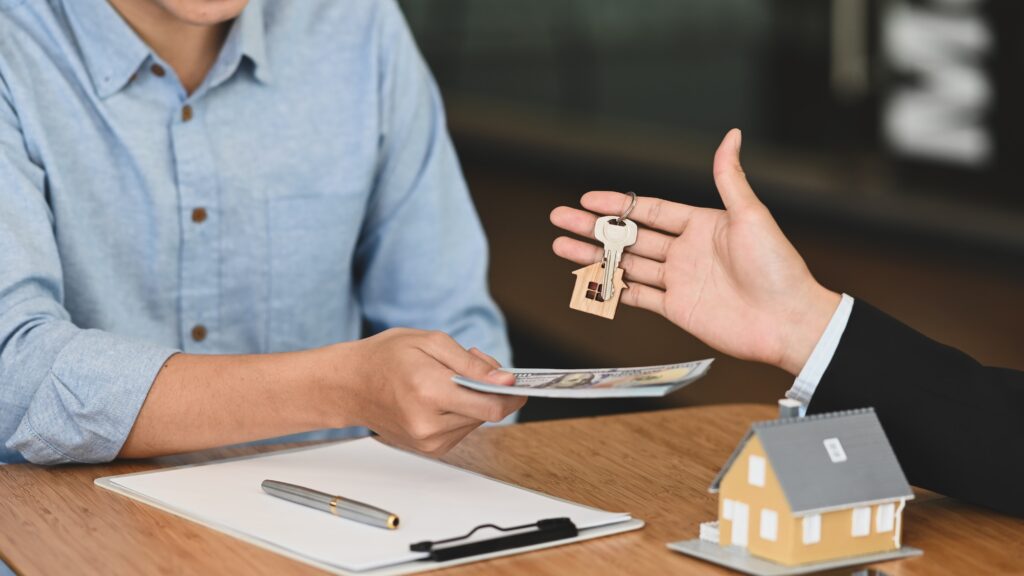 Realtor handing house keys in exchange for money. 