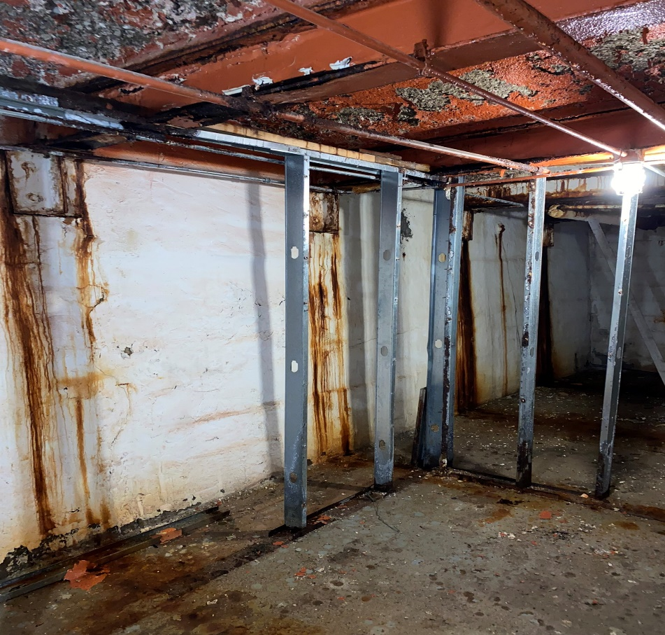 Underground vault adjacent to a GNP-managed Chicago property showing rust-stained walls, steel supports, and exposed ceiling structure before concrete fill work.